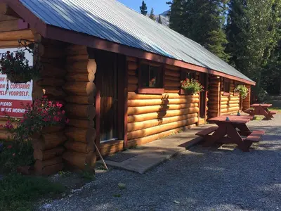 a log cabin with a picnic table in front of it at Double G Service in Muncho Lake