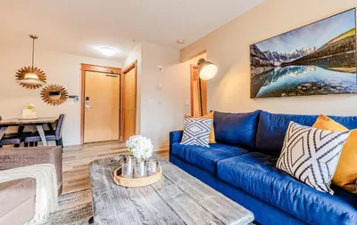 a living room with a blue couch and a table at Canmore Mountain Views -3Beds-Ski Stay Deals in Canmore