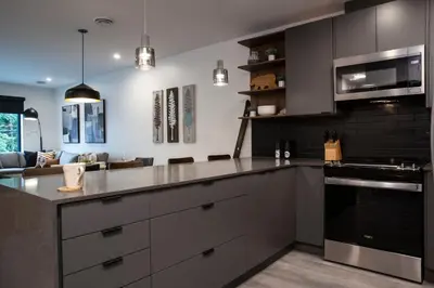 a kitchen with stainless steel appliances and a living room at Selkirk Staytion - Stylish Condo with Hot Tub in Revelstoke