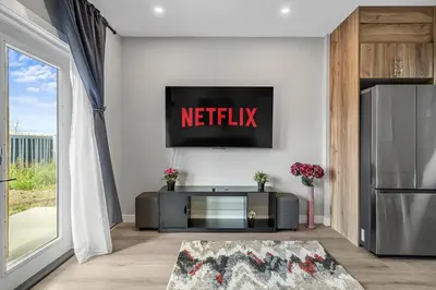 a living room with a netflix sign on the wall at Sunny Walk-out Unit, Free HiSpeed Wi-Fi and Parking, Near Grocery in Calgary