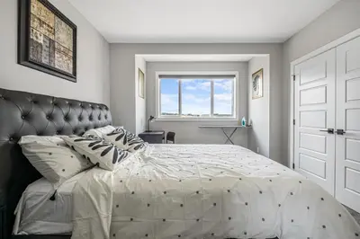 a bedroom with a large bed and a window at Sunny Walk-out Unit, Free HiSpeed Wi-Fi and Parking, Near Grocery in Calgary