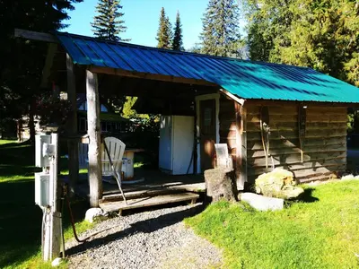 a wooden cabin with a blue tin roof and a chair at Bone Creek Wilderness Retreat in Blue River