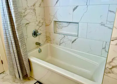 a white bath tub in a bathroom with marble tiles at Crescent Heights Majesty in Calgary