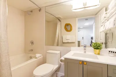 a white bathroom with a sink and a toilet and a tub at Renovated 1Bed-1Bath in Village with Pool, Hot Tub, and Sauna in Whistler