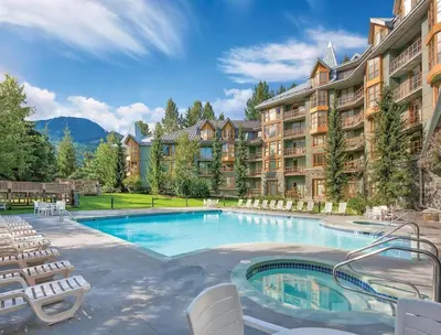 a large swimming pool with chairs and a hotel at Renovated 1Bed-1Bath in Village with Pool, Hot Tub, and Sauna in Whistler