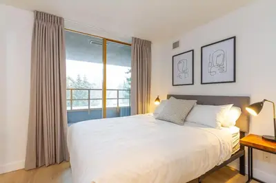 a bedroom with a large bed and a window at Renovated 2Bed-2Bath in Village with Pool, Hot Tub, and Sauna in Whistler