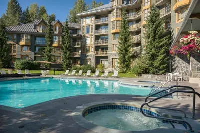 a swimming pool in front of a large apartment building at Renovated 2Bed-2Bath in Village with Pool, Hot Tub, and Sauna in Whistler