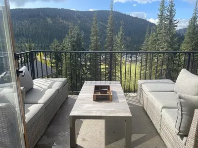 a patio with a couch and a table on a balcony at New! Luxury, Top Floor, Ski in/Ski Out, Private Hot Tub and Mountain Views in Sun Peaks