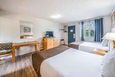 a hotel room with two beds and a desk at Bluebird Motel in Nanaimo