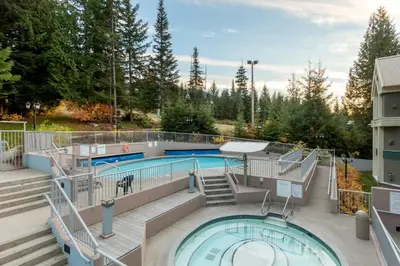 a pool on a building with stairs and a swimming pool at Woodrun Lodge 216 | Renovated Ski-In Ski-Out Condo w/ Free Parking, Pool, Hot Tub, & Gym in Whistler