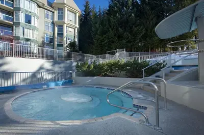 a swimming pool with a chair and a building at Woodrun Lodge 216 | Renovated Ski-In Ski-Out Condo w/ Free Parking, Pool, Hot Tub, & Gym in Whistler