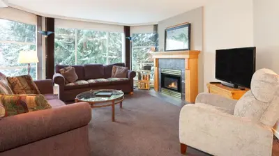 a living room with couches and a tv and a fireplace at Woodrun Lodge 217 | Ski-In Ski-Out Condo - Walk to Upper Village w/ Hot Tub, Pool + Free Parking in Whistler