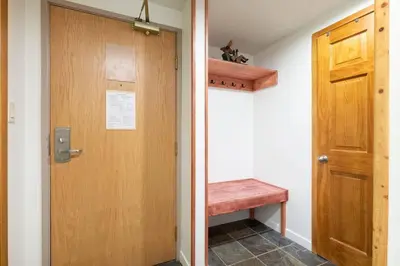 a hallway with a wooden door and a bench at Woodrun Lodge 214 | Ski-in-Ski-Out Condo, Heated Pool, Hot Tub, Gym in Whistler