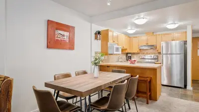 a kitchen with a wooden table and a stainless steel refrigerator at Woodrun Lodge 214 | Ski-in-Ski-Out Condo, Heated Pool, Hot Tub, Gym in Whistler