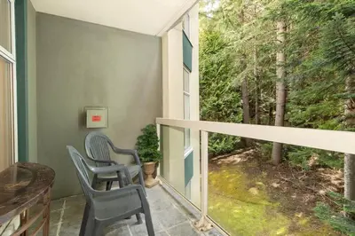 two chairs on a balcony with a view of trees at Woodrun Lodge 412 | Ski-In-Ski-Out, Pool, Hot Tub, & Free Parking in Whistler