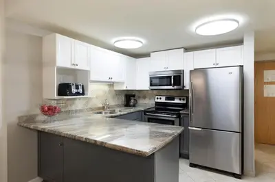 a kitchen with white cabinets and a stainless steel refrigerator at Woodrun Lodge 412 | Ski-In-Ski-Out, Pool, Hot Tub, & Free Parking in Whistler