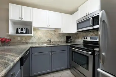 a kitchen with white cabinets and a stainless steel refrigerator at Woodrun Lodge 412 | Ski-In-Ski-Out, Pool, Hot Tub, & Free Parking in Whistler