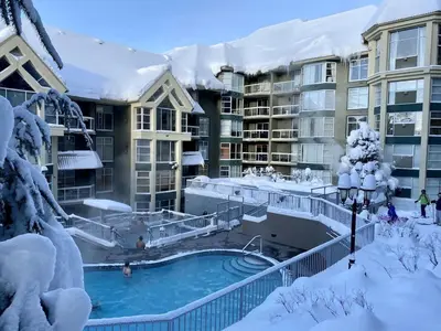 a resort with a swimming pool in the snow at Woodrun Lodge 211 | Ski-In Ski-Out Condo w/ Heated Pool, Hot Tub, Parking, & Gym in Whistler