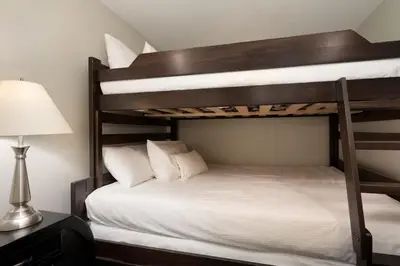 a bedroom with two bunk beds and a lamp at Woodrun Lodge 514 | Ski-In Ski-Out Condo w/ Pool, Hot Tub, Free Parking, Wifi & Laundry in Whistler