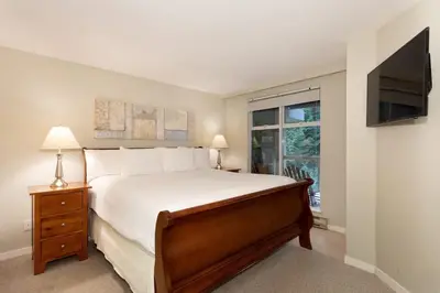 a bedroom with a large bed and a television at Woodrun Lodge 514 | Ski-In Ski-Out Condo w/ Pool, Hot Tub, Free Parking, Wifi & Laundry in Whistler