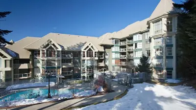 an apartment building with snow on the ground at Woodrun Lodge 514 | Ski-In Ski-Out Condo w/ Pool, Hot Tub, Free Parking, Wifi & Laundry in Whistler