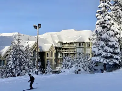 a man riding skis in the snow in front of a building at Woodrun Lodge 416 | Family Ski-In Ski-Out Condo, Hot Tub, Heated Pool, Parking & Laundry in Whistler