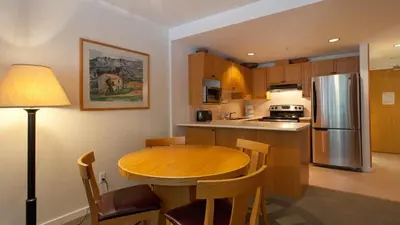 a kitchen with a wooden table and a refrigerator at Woodrun Lodge 416 | Family Ski-In Ski-Out Condo, Hot Tub, Heated Pool, Parking & Laundry in Whistler