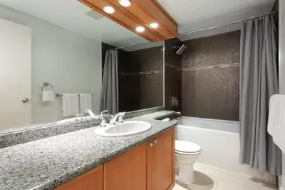 a bathroom with a sink and a toilet and a mirror at Woodrun Lodge 107 | New Listing! Ski-in, Ski-Out, Heated Pool, Hot Tub & Parking in Whistler