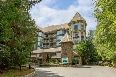 a large apartment building with a tower at Woodrun Lodge 107 | New Listing! Ski-in, Ski-Out, Heated Pool, Hot Tub & Parking in Whistler