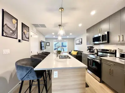 a kitchen with a counter and a kitchen island with bar stools at Brand New 2BR Condo with Outdoor Swimming Pool and Hot Tub in Canmore