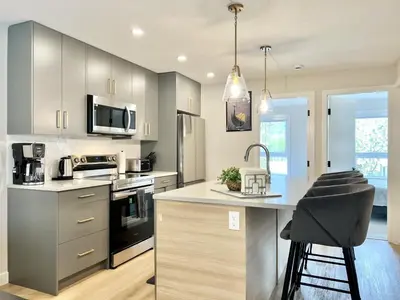 a kitchen with a counter with a sink and a stove at Brand New 2BR Condo with Outdoor Swimming Pool and Hot Tub in Canmore