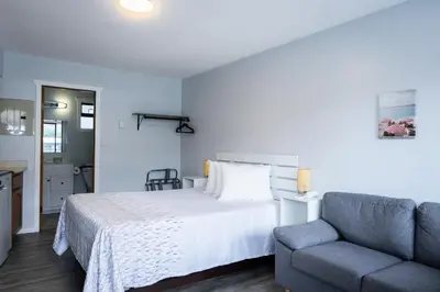 a bedroom with a bed and a blue couch at Poplars Motel on the lake in Osoyoos