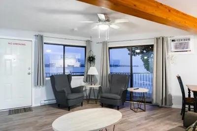 a living room with chairs and a table and windows at Poplars Motel on the lake in Osoyoos