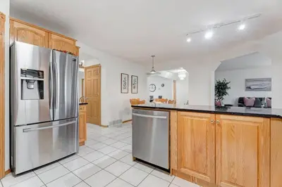 a kitchen with wooden cabinets and a stainless steel refrigerator at Coral Springs Lakefront Retreat in Calgary