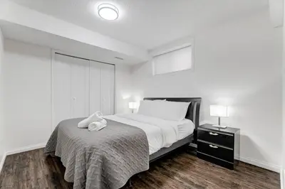 a white bedroom with a bed with a towel on it at Coral Springs Lakefront Retreat in Calgary