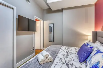 a bedroom with a bed and a flat screen tv at Cozy 2BR Condo with King Bed and City Views in Calgary