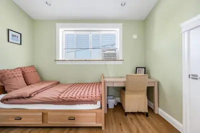 a bedroom with a bed and a desk and a window at Three bedrooms new laneway house near public transit & FIFA training site in Vancouver