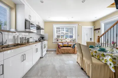 a kitchen with white cabinets and a table in it at Three bedrooms new laneway house near public transit & FIFA training site in Vancouver