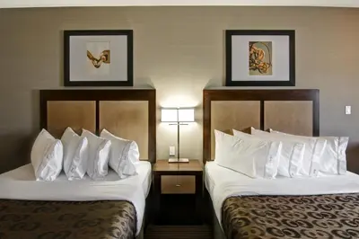 two beds in a hotel room with white pillows at Canalta Lac La Biche in Lac La Biche