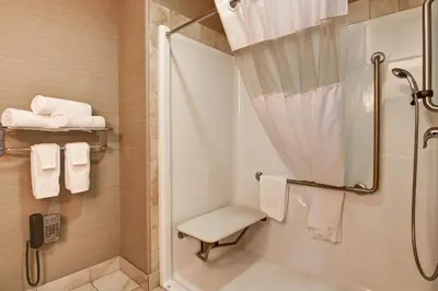 a bathroom with a shower and a toilet and towels at Canalta Lac La Biche in Lac La Biche