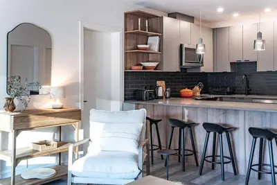 a kitchen with a bar with stools and a table at Snowed Inn - Stunning 3 Bedroom Condo in Revelstoke