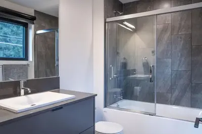 a bathroom with a shower and a sink and a toilet at Snowed Inn - Stunning 3 Bedroom Condo in Revelstoke