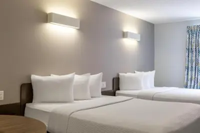 two beds with white pillows in a hotel room at Motel 6 Airdrie in Airdrie