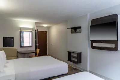 a hotel room with a bed and a television at Motel 6 Airdrie in Airdrie