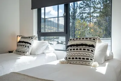 a bedroom with two beds with white pillows and a window at Mountainview Escape by Revelstoke Vacations in Revelstoke