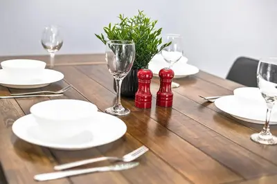 a wooden table with white plates and wine glasses at Large Townhome Near Anthony Henday in Ellerslie with Driveway & Visitor Parking, King Bed, 4 Queen Beds, Fully Equipped Kitchen & More! in Edmonton