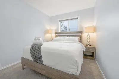 a bedroom with a large white bed and a window at Large Townhome Near Anthony Henday in Ellerslie with Driveway & Visitor Parking, King Bed, 4 Queen Beds, Fully Equipped Kitchen & More! in Edmonton
