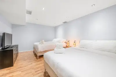 a bedroom with two beds and a flat screen tv at Large Townhome Near Anthony Henday in Ellerslie with Driveway & Visitor Parking, King Bed, 4 Queen Beds, Fully Equipped Kitchen & More! in Edmonton