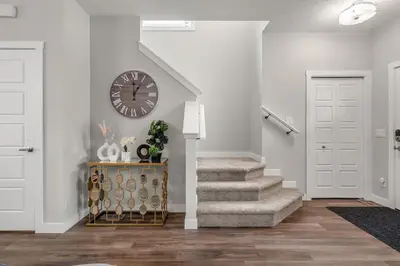 a hallway with a clock on the wall and stairs at Extra Large House with AC, Banff Access, Sleep 12, BBQ, 4 Bedrooms & 2 Sleeper Sofa Beds in Airdrie