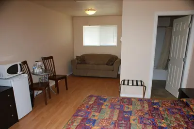 a bedroom with a bed and a living room at Elks Motel in Keremeos